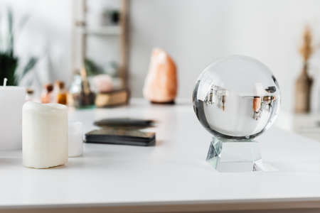 Glass orb near candles and blurred tarot cards on tableの写真素材