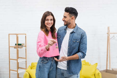 Cheerful woman holding key near arabian boyfriend at homeの写真素材