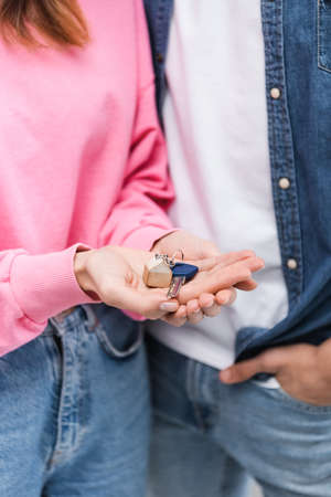 Cropped view of woman holding key near blurred boyfriend