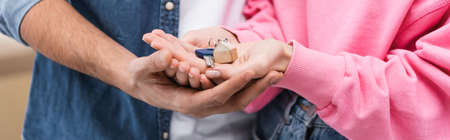 Cropped view of couple holding key at home, bannerの写真素材