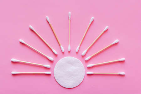 flat lay of ear sticks around white cotton pad on pink background, top viewの写真素材