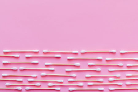 horizontal rows of cotton swabs on pink background, top viewの写真素材