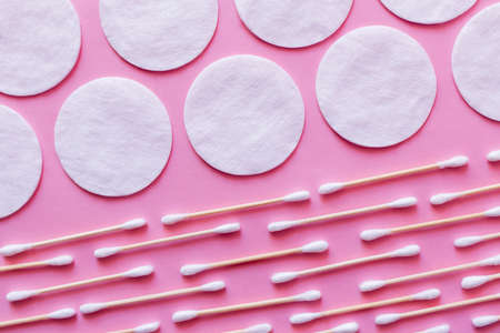 rows of white cotton pads and ear sticks on pink background, top viewの写真素材