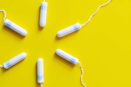 circle of hygienic tampons on bright yellow background, top viewの写真素材