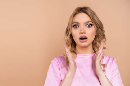 astonished woman with open mouth showing wow gesture isolated on beige