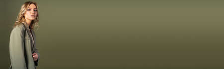 charming woman in grey blazer looking at camera isolated on green with copy space, bannerの写真素材