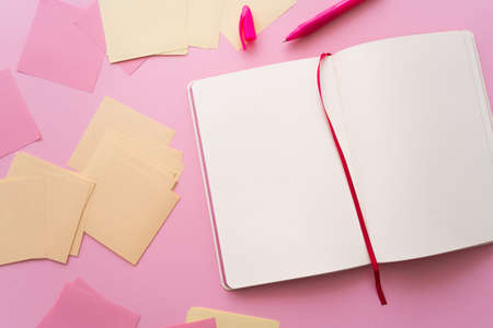 top view of pen near open notebook and paper notes on pink
