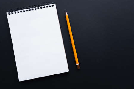 top view of empty notebook and pencil on black