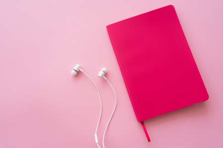 top view of earphones near bright notebook on pinkの写真素材