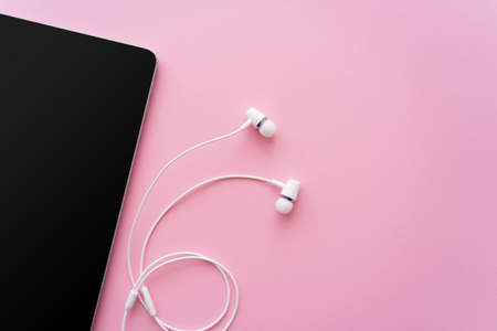 top view of digital tablet with blank screen near earphones on pinkの写真素材