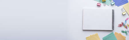top view of blank notebook near colorful stationery on white, banner