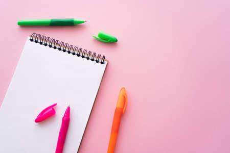top view of colorful pens near blank notebook on pinkの写真素材