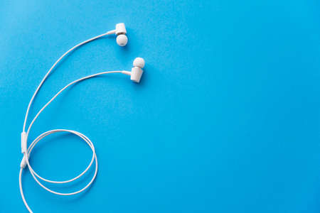 top view of white wired earphones on blueの写真素材