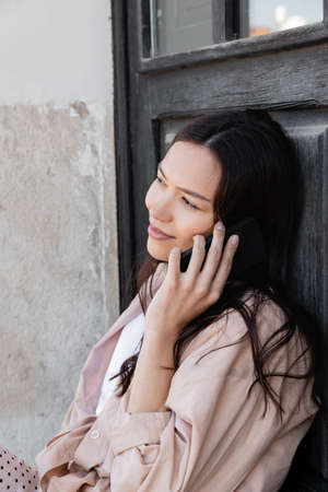 smiling woman in beige shirt talking on mobile phone outdoors