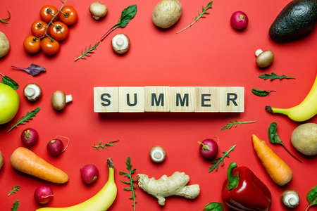 Flat lay with summer lettering on wooden cubes near fresh food on red backgroundの写真素材