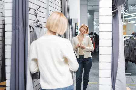 Blurred woman looking at mirror in dressing room in second handの写真素材
