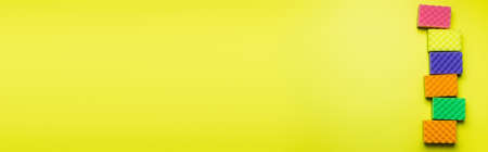 top view of bright multicolored sponges on yellow background with copy space, bannerの写真素材