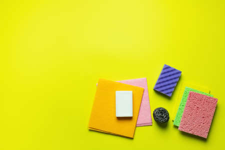 top view of multicolored dishrags, scouring pad, sponge cloths, metal scrubber and soap on yellow backgroundの写真素材