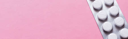 close up view of blister pack with white round shape pills isolated on pink, banner
