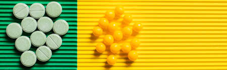 top view of round shape pills and vitamins on textured green and yellow background, bannerの写真素材