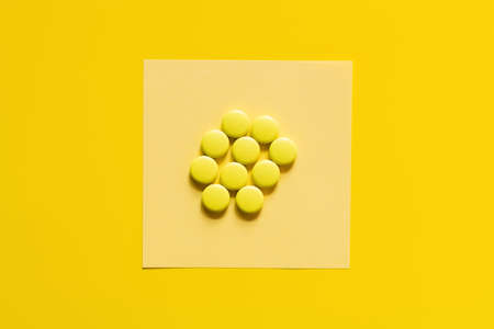 top view of round shape pills on paper note on yellow