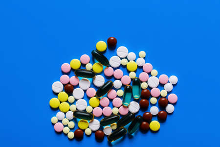 top view of different colorful pills and capsules on bright blue background