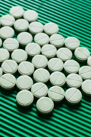 close up view of round shape medication on textured green background