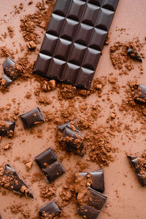 Top view of natural dark chocolate and cocoa on brown background