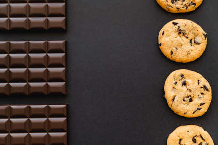 Flat lay with chocolate bars and cookies on black backgroundの写真素材