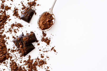 Top view of cocoa in spoon near dark chocolate pieces on white background with copy space