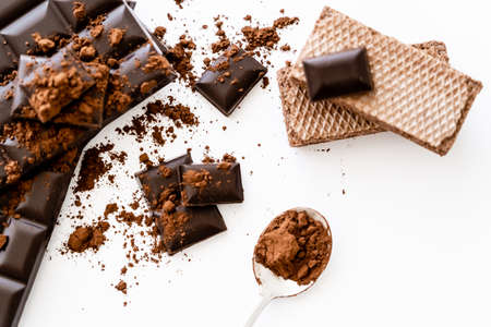 Top view of cocoa in spoon, chocolate bars and waffles on white background