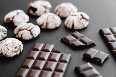 Close up view of chocolate bars and biscuits on black background