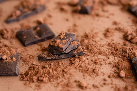 Close up view of cocoa powder on chocolate pieces on brown backgroundの写真素材