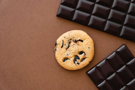 Top view of cookie near dark chocolate bars on brown backgroundの写真素材