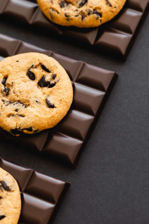 Top view of delicious cookies on dark chocolate on black surface