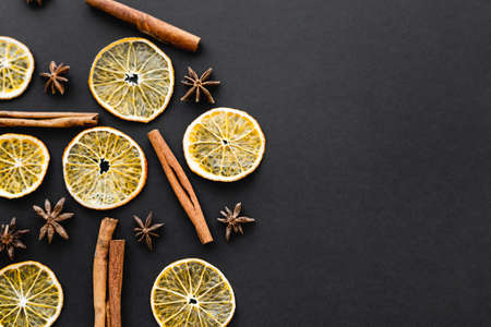 Top view of dry anise, orange slices and cinnamon sticks on black backgroundの写真素材
