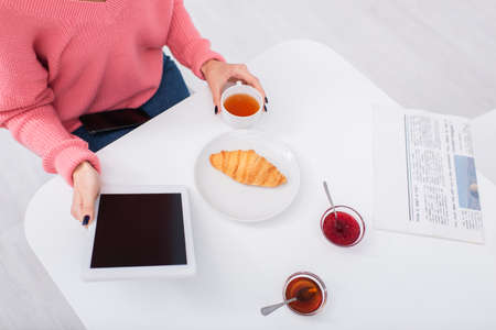 cropped view of woman using digital tablet during breakfast