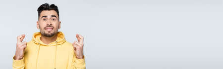nervous bookmaker holding crossed fingers for success isolated on grey, banner