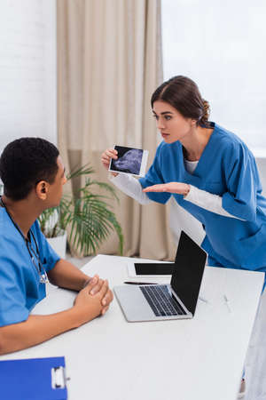 Veterinarian pointing at ultrasound scan of animal near african american colleague in clinicの写真素材