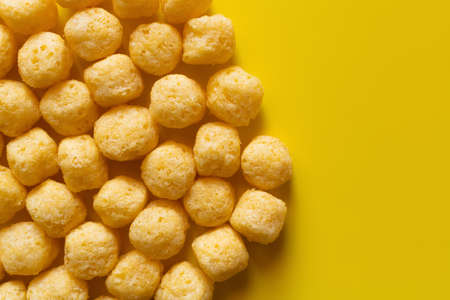 top view of puffed and salty cheese pops on yellow