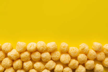 flat lay of puffed and tasty cheese pops on yellowの写真素材