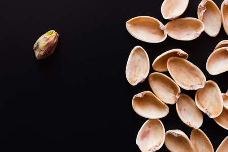 top view of nutshells and tasty pistachio nut isolated on blackの写真素材