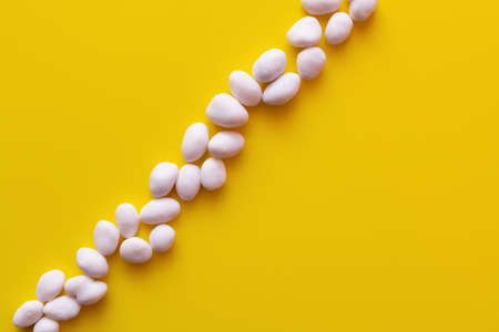 top view of row with peeled pine nuts on yellow backgroundの写真素材