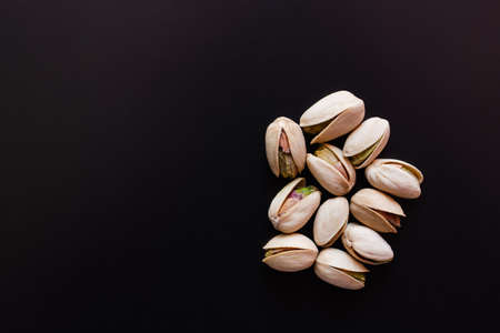 top view of cracked and salty pistachios isolated on blackの写真素材