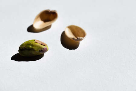 cracked green and salty pistachio near blurred nutshells on white backgroundの写真素材