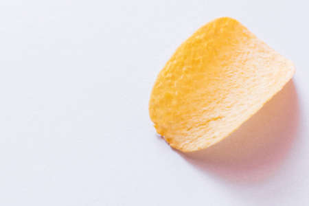 top view of single potato chip with salt on whiteの写真素材