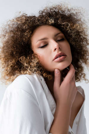 Portrait of pretty curly model touching face isolated on whiteの写真素材
