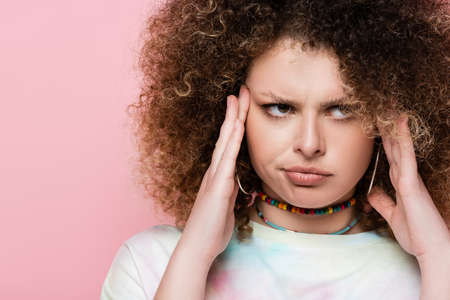 Portrait of pensive curly woman isolated on pinkの写真素材