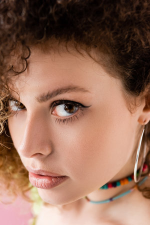 Close up view of curly woman looking at camera isolated on pinkの写真素材