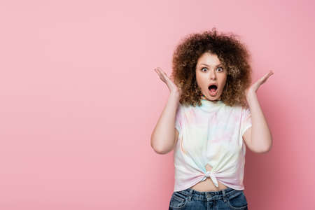 Astonished woman in t-shirt looking at camera on pink backgroundの写真素材